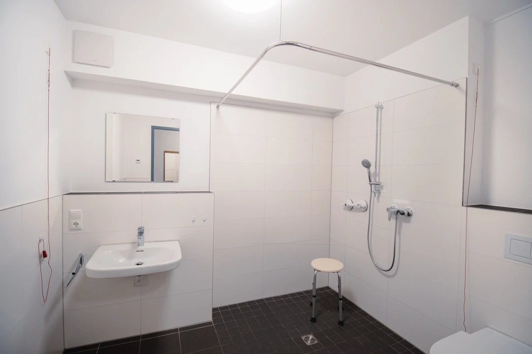 Barrierefreies Bad mit bodengleicher Dusche, Duschhocker und unterfahrbarem Waschbecken