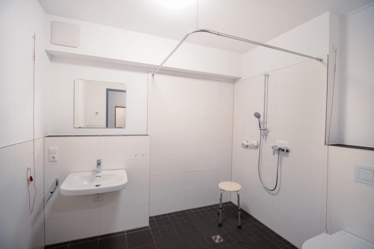 Barrierefreies Bad mit bodengleicher Dusche, Duschhocker und unterfahrbarem Waschbecken