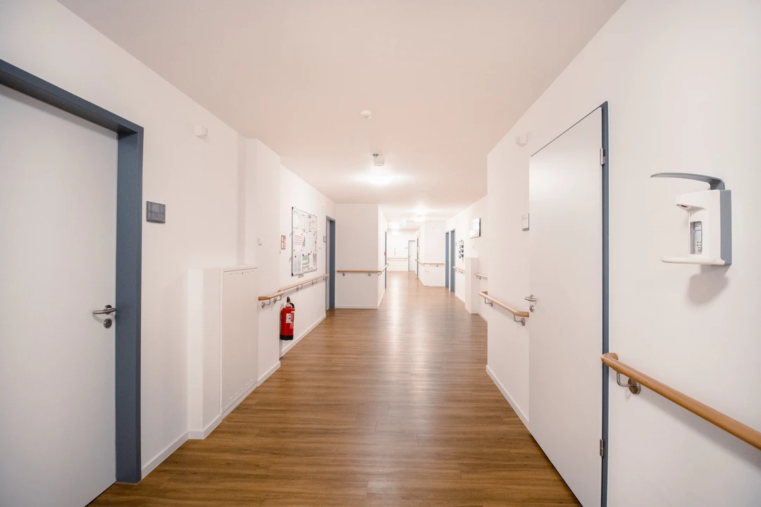 Heller Flur mit Handläufen an beiden Wänden und Holzboden